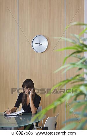 Stock Photography - Business woman using cell phone in conference room. Fotosearch