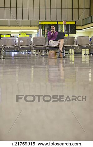 Business woman using laptop and mobile phone in airport lobby View Large Photo Image Stock Photography - Business woman using laptop and mobile phone in airport lobby. Fotosearch
