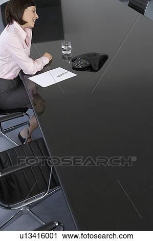Business woman using mobile phone at conference room table View Large Photo Image Stock Image - Business woman using mobile phone at conference room table. Fotosearch