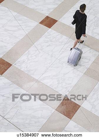 Stock Photo - Business woman walking with suitcase elevated view back view. Fotosearch