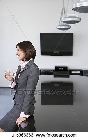 Business woman with drink leaning against table in conference room View Large Photo Image Stock Image - Business woman with drink leaning against table in conference room. Fotosearch