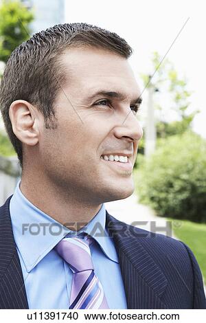 Stock Image - Businessman looking away smiling outdoors close-up. Fotosearch
