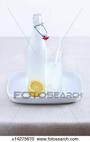 Stock Image - Ceramic bottle lemonade glass and lemon on tray. Fotosearch