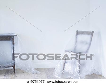 Chair and table covered by plastic in empty room View Large Photo Image Stock Photo - Chair and table covered by plastic in empty room. Fotosearch