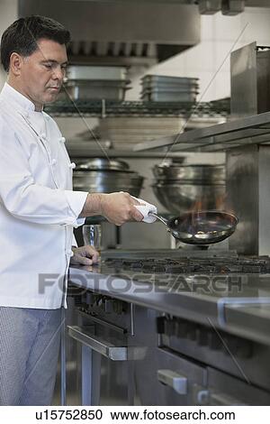 Chef cooking food using frying pan in kitchen View Large Photo Image Stock Image - Chef cooking food using frying pan in kitchen. Fotosearch