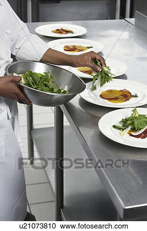 Stock Image - Chef preparing salad in kitchen mid section. Fotosearch