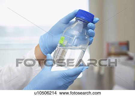 Chemist holding bottle of solution in laboratory close-up of hands View Large Photo Image Picture - Chemist holding bottle of solution in laboratory close-up of hands. Fotosearch