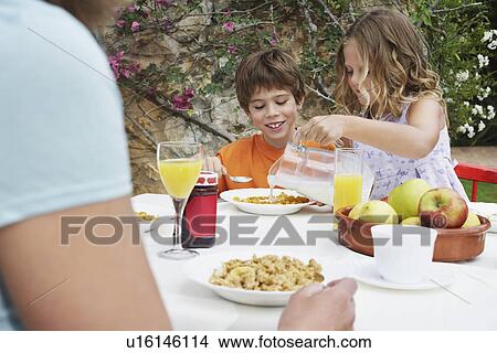 Children (5-6) at table girl pouring milk onto cereal View Large Photo Image Picture - Children (5-6) at table girl pouring milk onto cereal. Fotosearch