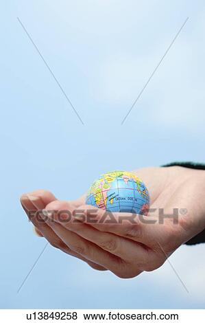 Stock Photo - Close-up of hand holding globe. Fotosearch