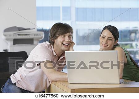 Colleagues using laptop at desk in office View Large Photo Image Stock Image - Colleagues using laptop at desk in office. Fotosearch