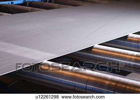 Stock Photo - Continuous sheet of metallic material being fed through machine. Fotosearch