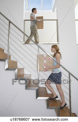Stock Photo - Couple carrying boxes upstairs in new home. Fotosearch