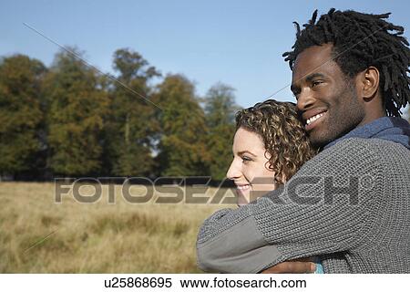 Couple embracing in field View Large Photo Image Stock Photography - Couple embracing in field. Fotosearch