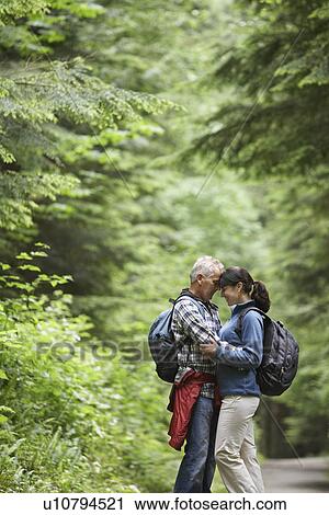 Stock Image - Couple embracing in forest side view. Fotosearch