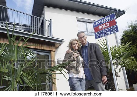 Couple embracing outside new home with sold sign portrait View Large Photo Image Stock Image - Couple embracing outside new home with sold sign portrait. Fotosearch