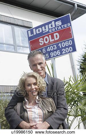 Couple embracing outside new home with sold sign portrait View Large Photo Image Stock Image - Couple embracing outside new home with sold sign portrait. Fotosearch