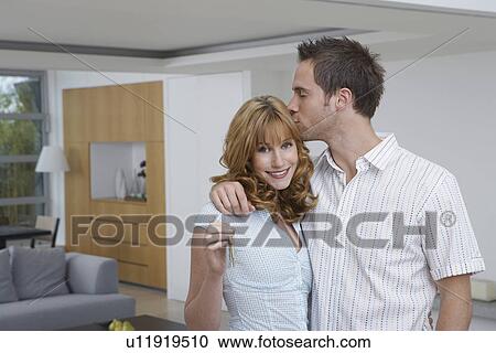 Couple embracing woman holding key in new home View Large Photo Image Stock Image - Couple embracing woman holding key in new home. Fotosearch