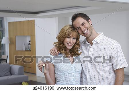 Couple embracing woman holding key in new home portrait View Large Photo Image Stock Photograph - Couple embracing woman holding key in new home portrait. Fotosearch