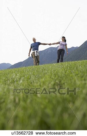 Couple holding hands grass in foreground View Large Photo Image Stock Photo - Couple holding hands grass in foreground. Fotosearch