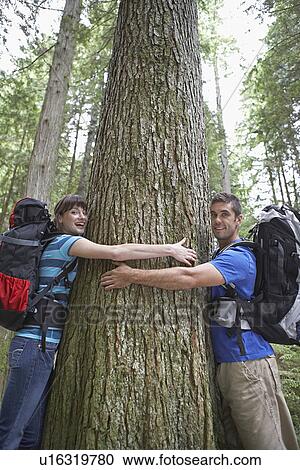 Couple hugging tree in forest portrait View Large Photo Image Stock Image - Couple hugging tree in forest portrait. Fotosearch