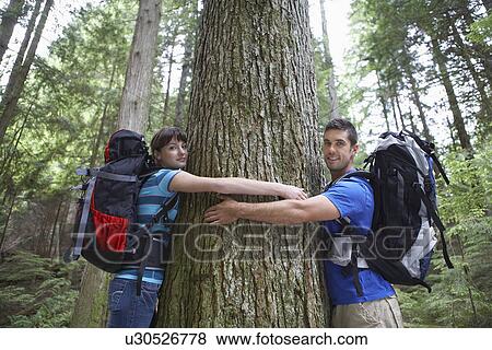 Stock Photo - Couple hugging tree in forest portrait. Fotosearch