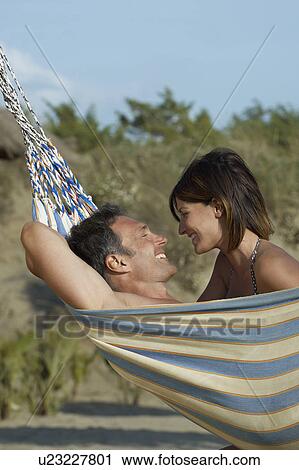 Stock Image - Couple in hammock laughing profile. Fotosearch