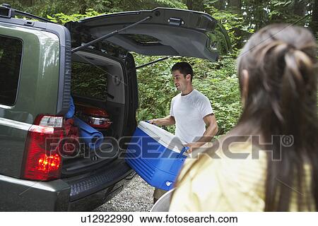 Stock Image - Couple loading car in countryside. Fotosearch