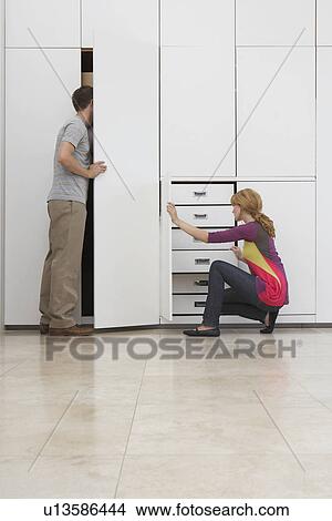 Couple looking in wardrobe in empty apartment View Large Photo Image Picture - Couple looking in wardrobe in empty apartment. Fotosearch