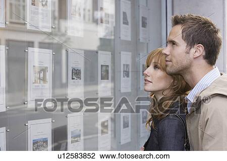 Couple looking in window outside estate agents View Large Photo Image Stock Image - Couple looking in window outside estate agents. Fotosearch