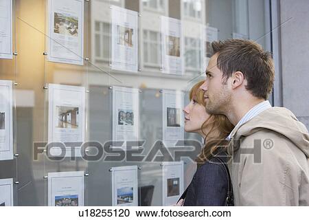 Couple looking in window outside estate agents View Large Photo Image Stock Image - Couple looking in window outside estate agents. Fotosearch