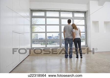 Couple looking out of window in empty apartment View Large Photo Image Picture - Couple looking out of window in empty apartment. Fotosearch