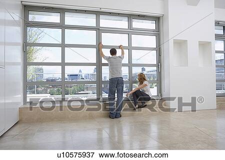 Couple looking out of window in empty apartment View Large Photo Image Stock Photo - Couple looking out of window in empty apartment. Fotosearch