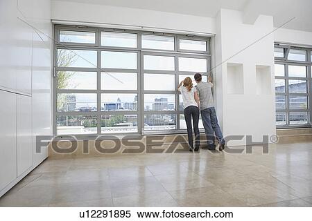 Couple looking out of window in empty apartment View Large Photo Image Stock Photography - Couple looking out of window in empty apartment. Fotosearch
