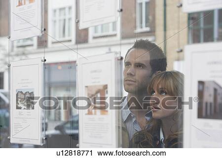 Couple looking through window at estate agents View Large Photo Image Stock Image - Couple looking through window at estate agents. Fotosearch