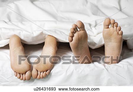 Couple lying in bed low section close up of feet View Large Photo Image Stock Image - Couple lying in bed low section close up of feet. Fotosearch