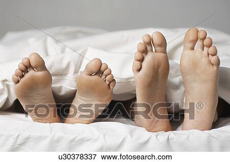 Couple lying in bed low section close up of feet View Large Photo Image Stock Photo - Couple lying in bed low section close up of feet. Fotosearch