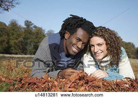 Couple lying in grass with autumn leaves View Large Photo Image Stock Image - Couple lying in grass with autumn leaves. Fotosearch