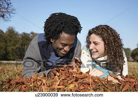 Couple lying in grass with autumn leaves View Large Photo Image Stock Photo - Couple lying in grass with autumn leaves. Fotosearch