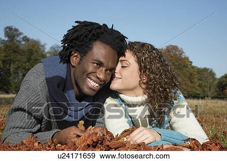 Couple lying in grass with autumn leaves View Large Photo Image Stock Photo - Couple lying in grass with autumn leaves. Fotosearch