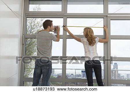 Stock Image - Couple measuring apartment window. Fotosearch
