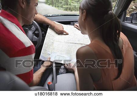 Stock Photo - Couple observing map in car. Fotosearch