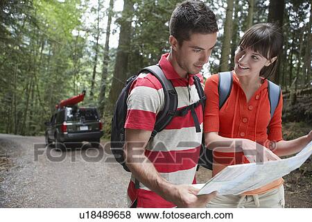 Stock Photo - Couple observing map in forest. Fotosearch