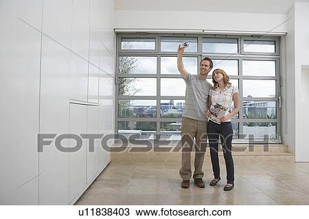 Stock Image - Couple photographing empty apartment. Fotosearch