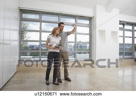 Couple photographing empty apartment View Large Photo Image Stock Image - Couple photographing empty apartment. Fotosearch