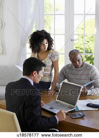 Couple sitting at dining table with financial advisor View Large Photo Image Stock Photo - Couple sitting at dining table with financial advisor. Fotosearch