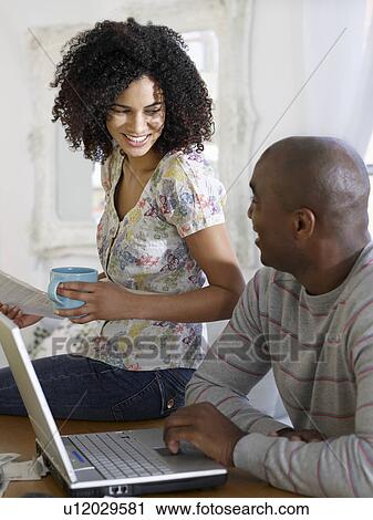 Couple sitting at table using laptop and holding bills View Large Photo Image Stock Image - Couple sitting at table using laptop and holding bills. Fotosearch
