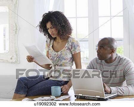 Couple sitting at table using laptop and reading document View Large Photo Image Stock Image - Couple sitting at table using laptop and reading document. Fotosearch