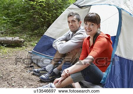 Stock Photo - Couple sitting in tent entrance smiling portrait. Fotosearch