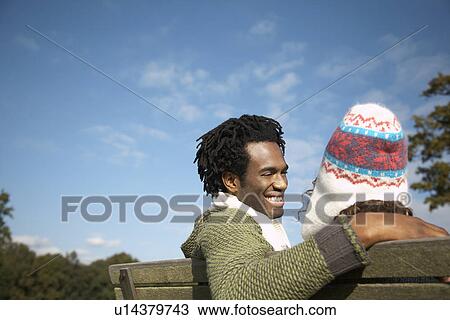 Stock Image - Couple sitting on bench back view. Fotosearch