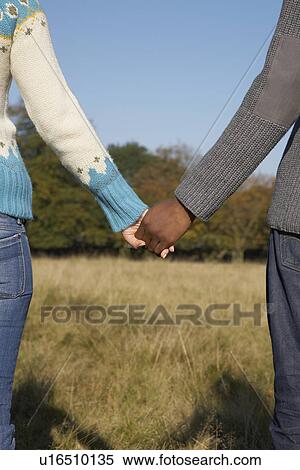 Couple standing in field holding hands mid section back view View Large Photo Image Stock Photography - Couple standing in field holding hands mid section back view. Fotosearch